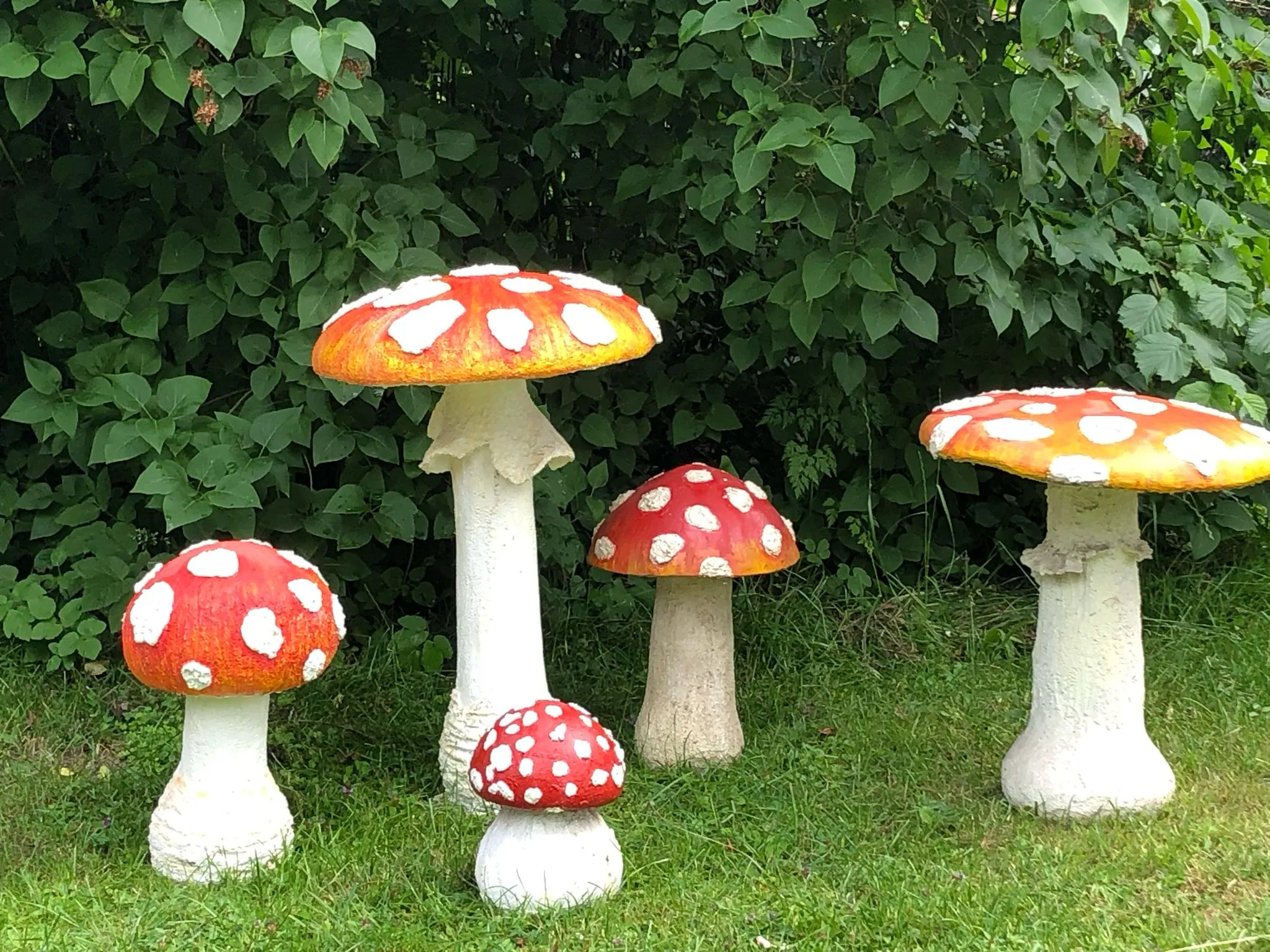 Gruppe von vier Fliegenpilz-Skulpturen aus Beton im Garten